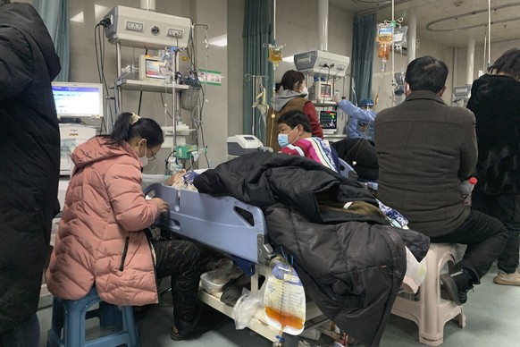 23.12.2022, China, Bazhou: Angehörige versammeln sich in der Notaufnahme des Langfang No. 4 People's Hospital in der Stadt Bazhou in der nordchinesischen Provinz Hebei neben den Betten der erkrankten  ...