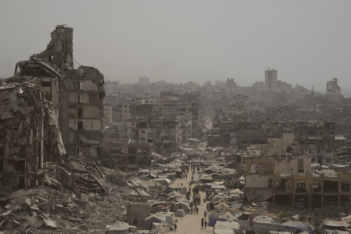 ARCHIV - 29.07.2025, Palästinensische Gebiete, Gaza-Stadt: Menschen gehen eine Straße entlang, die von Gebäuden umgeben ist, die durch israelische Bombardierungen im Gazastreifen zerstört wurden. (zu  ...