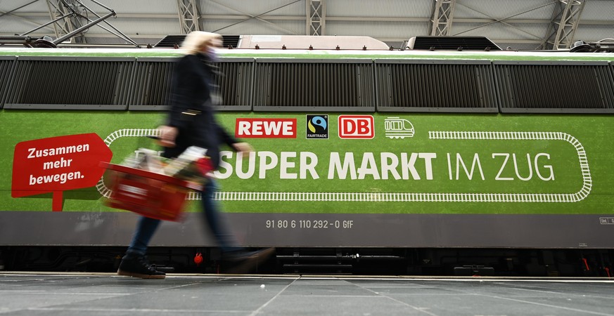 ILLUSTRATION - Eine Frau geht bei der Vorstellung des temporären Projekts &quot;Fairer Supermarkt im Zug&quot; im Frankfurter Hauptbahnhof an der Lok mit der Aufschrift &quot;Dein Supermarkt im Zug&qu ...