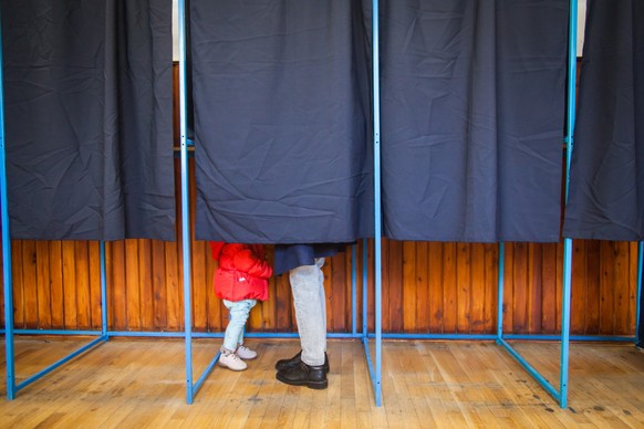 People vote in a voting booth at a polling station.