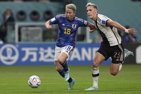 Japan's Takuma Asano, left, fights for the ball with Germany's Nico Schlotterbeck, on his way to score his side's second goal during the World Cup group E soccer match between Germany a ...