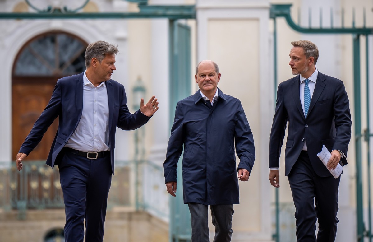 ARCHIV - 29.08.2023, Brandenburg, Meseberg: Bundeskanzler Olaf Scholz (SPD, M) kommt zwischen Christian Lindner (FDP, l), Bundesminister der Finanzen, und Robert Habeck (Bündnis 90/Die Grünen, r), Bun ...