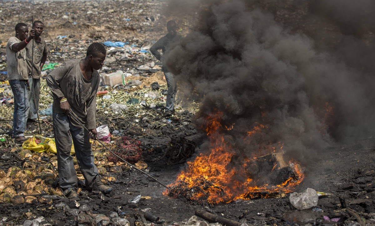 Junge afrikanische Maenner verbrennen Elektroschrott auf der groessten Elektromuelldeponie Afrikas in Agbogbloshie, einem Stadtteil von Ghanas Hauptstadt. Hier verbrennt man ausgediente Altgeraete, um ...