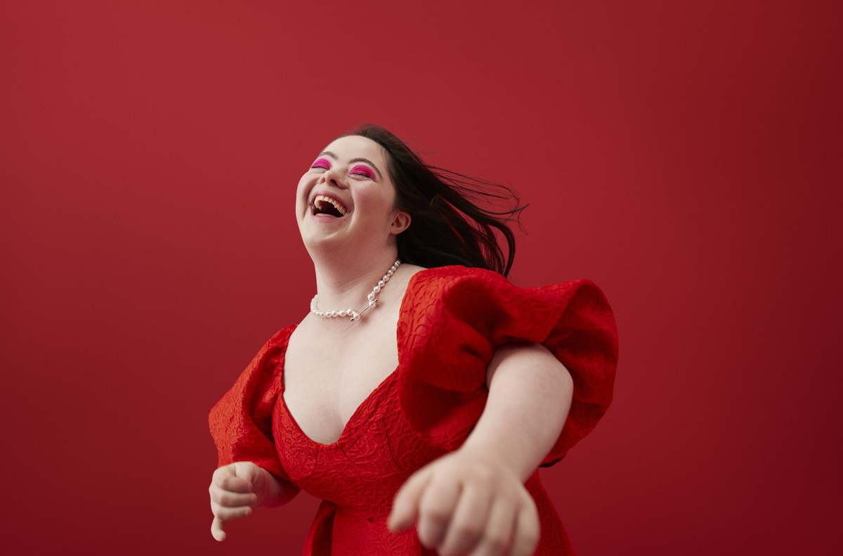 Happy young woman with with down syndrome laughing against red background