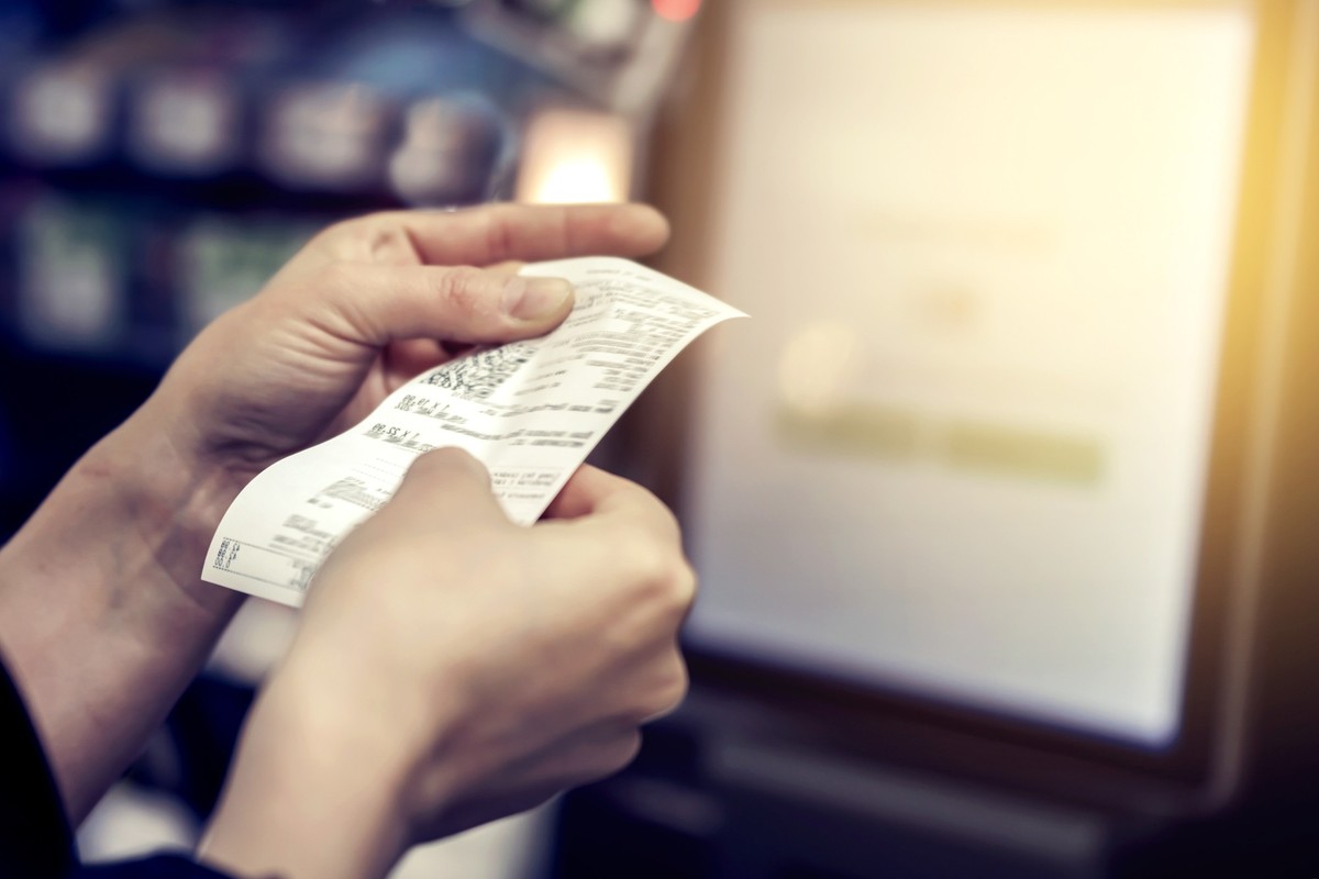 the girl looks at the receipt in the store.