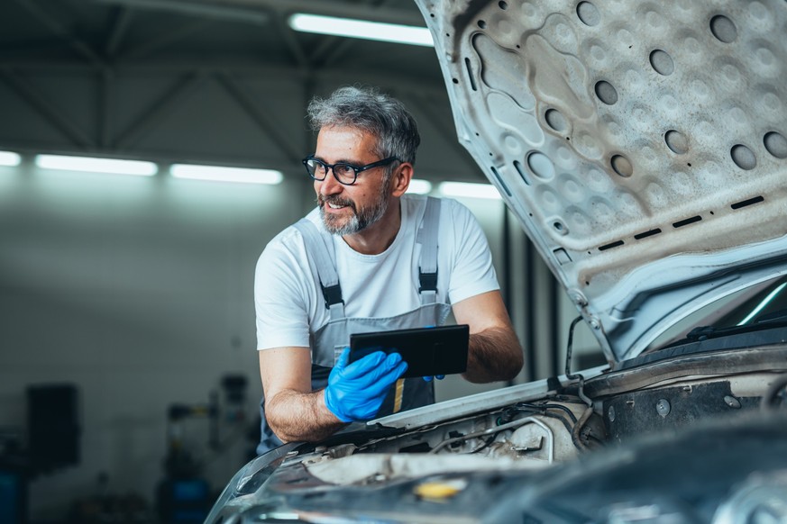 worker using tablet for car diagnostic service