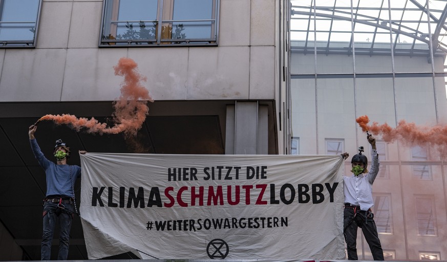 16.06.2020, Berlin: Aktivisten der Umweltschutzbewegung Extinction Rebellion (XR) stehen mit farbigen Rauchfackeln einem Transparent vor dem Haus des Bundesverbandes der Deutschen Industrie (BDI) mit  ...