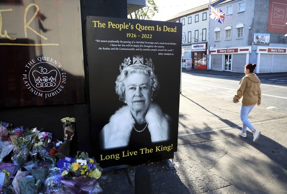 FILE - A woman walks past a picture of Queen Elizabeth II on the Loyalist Shankill Road in west Belfast, Sept. 10, 2022. Britain's longest-reigning monarch and a rock of stability across much of a tur ...