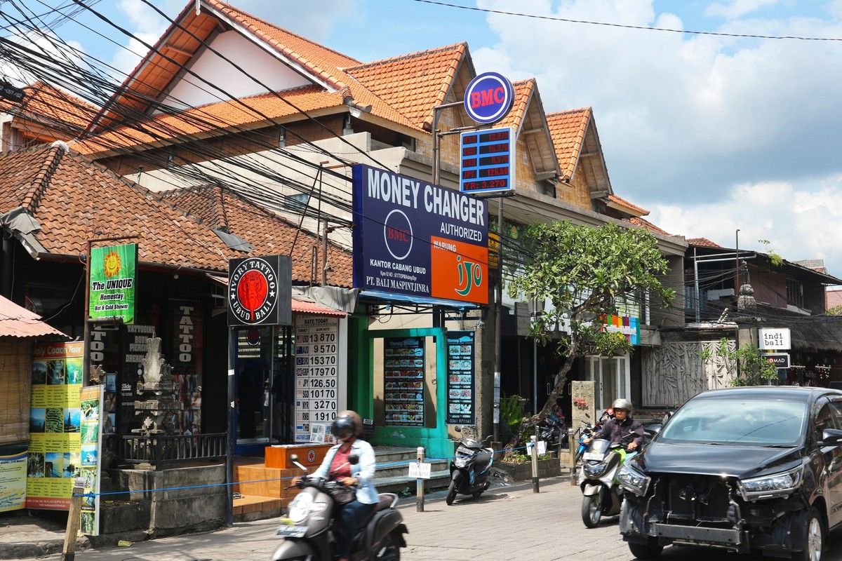 Ubud, Bali, Indonesia - December 26, 2019: Authorized money changer and traffic on the street Jl. Raya