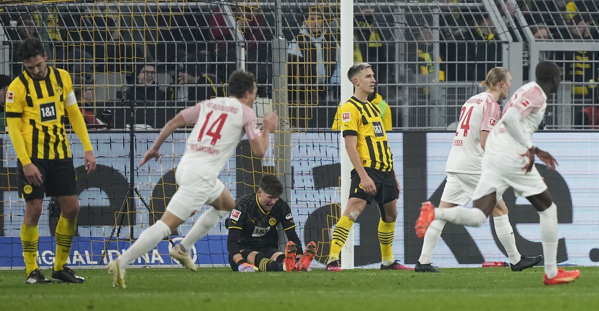 Dortmund&#039;s Mats Hummels, goalkeeper Gregor Kobel, and Nico Schlotterbeck, in black and yellow from left, show their dejection as Augsburg players run to celebrate after scoring their side&#039;s  ...