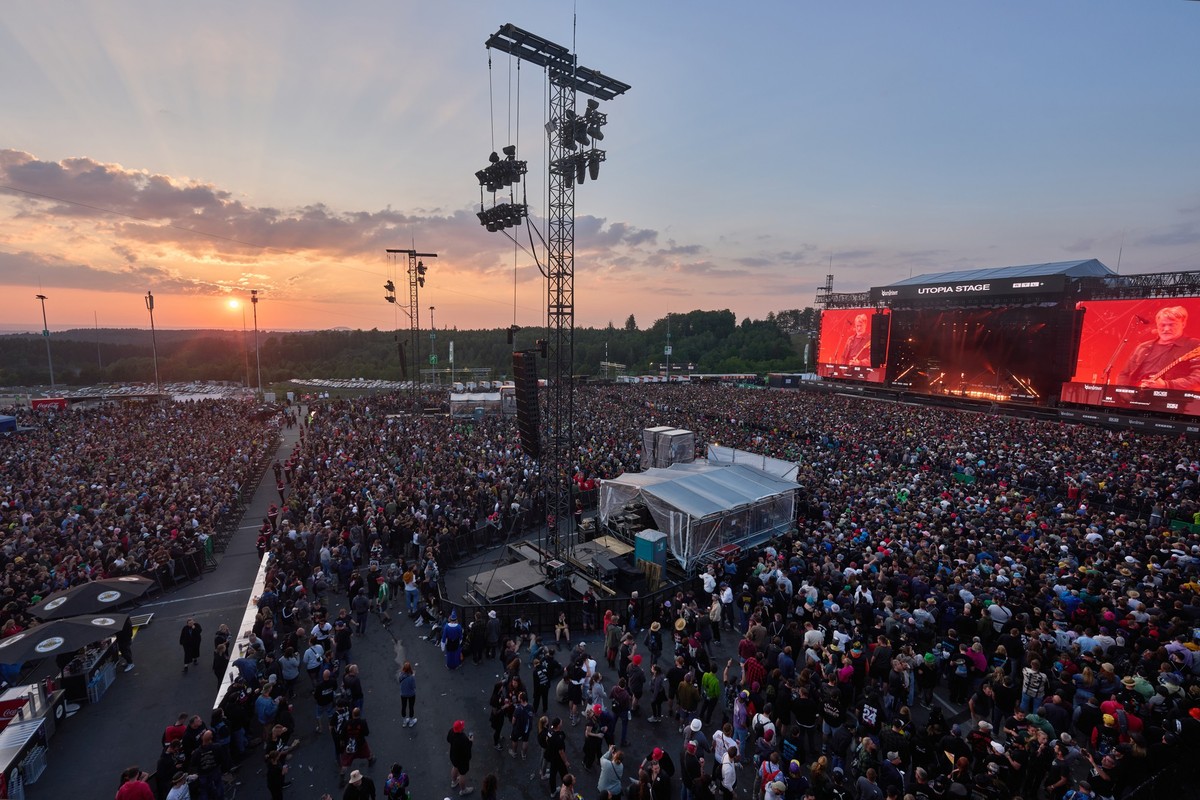 ARCHIV - 07.06.2024, Rheinland-Pfalz, Nürburg: Rockfans stehen beim Auftritt der amerikanischen Rockband "Queens of the Stoneage" beim Open-Air-Festival "Rock am Ring" vor der Utop ...