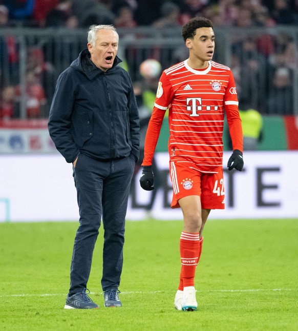 04.04.2023, Bayern, München: Fußball: DFB-Pokal, Bayern München - SC Freiburg, Viertelfinale in der Allianz Arena. Trainer Christian Streich (l) von Freiburg und Jamal Musiala von München stehen nach  ...