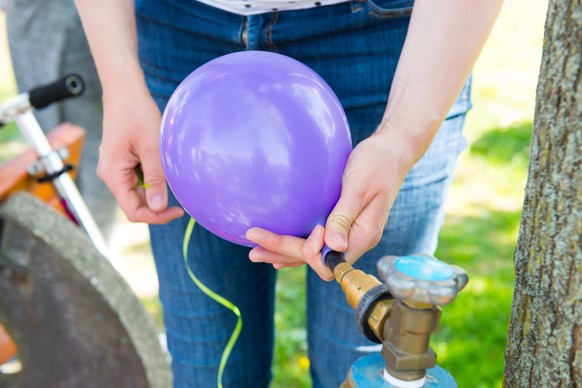 woman filling violet balloon with helium Copyright: xarnoaltixx Panthermedia24769950