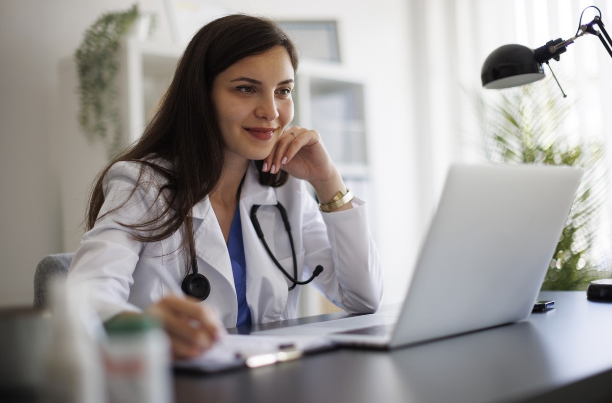 Smiling female doctor working on laptop in the office