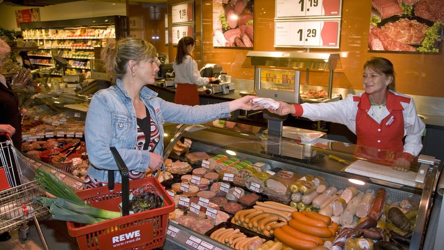 01.04.2008, Koeln, Nordrhein-Westfalen, Deutschland - REWE - Eine Frau laesst sich an der Wursttheke bedienen. Der REWE-City-Markt ist ein kleinflaechiger Supermarkt mit Vollsortiment, der Supermarkt  ...