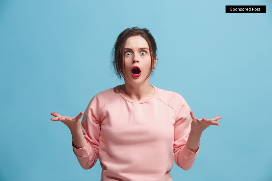 What is it. The female portrait isolated on blue studio backgroud. Anger. The young emotional angry, scared woman looking at camera.The human emotions, facial expression concept. Trendy colors