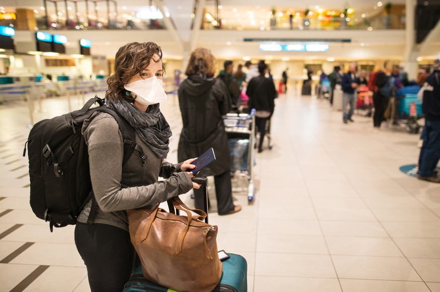 Woman waiting in a long line for a flight wearing a N95 face mask during a global pandemic