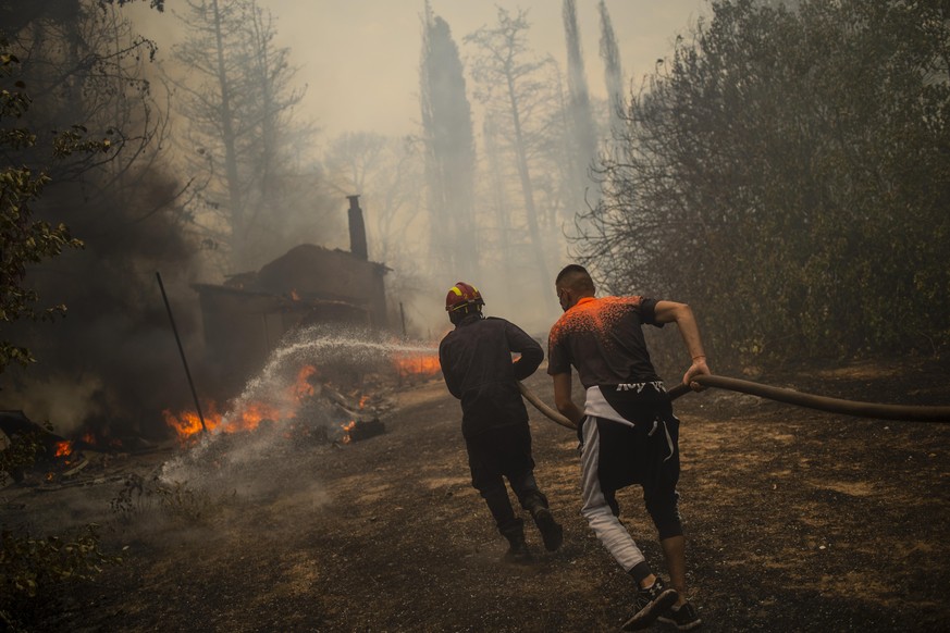 Feuerwehrleute versuchen einen Waldbrand in einem Waldgebiet nördlich von Athen zu löschen. Seit den frühen Morgenstunden fachten starke Westwinde am Freitag die zahlreichen Feuer weiter an.