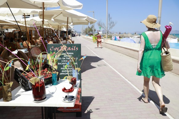 09.08.2022, Spanien, Santa Margalida: Touristen gehen an einer Bar an der Promenade des Strandes von Can Picafort auf Mallorca vorbei. Foto: Clara Margais/dpa +++ dpa-Bildfunk +++
