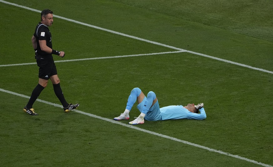 Referee Raphael Claus, left, watches Iran's goalkeeper Alireza Beiranvand is laying on the ground after sustaining an injury during the World Cup group B soccer match between England and Iran at the K ...