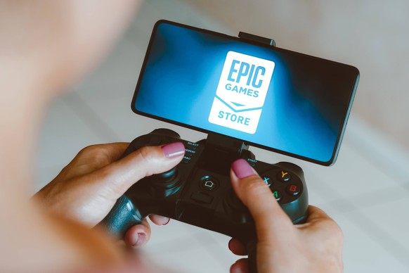 Logos displayed on smartphones in Brazil - 04 Dec 2023 In this photo illustration, the Epic Games Store logo is displayed on a smartphone screen as a person plays on a gaming gamepad. Brazil Copyright ...