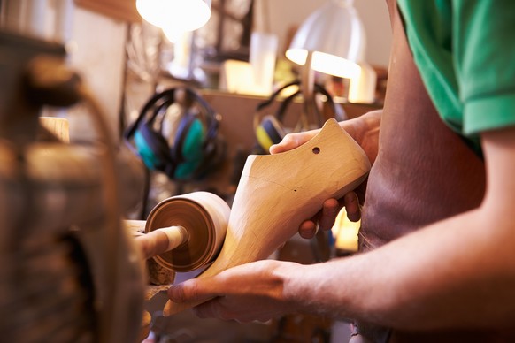 Hands of shoemaker shaping shoe lasts in a workshop