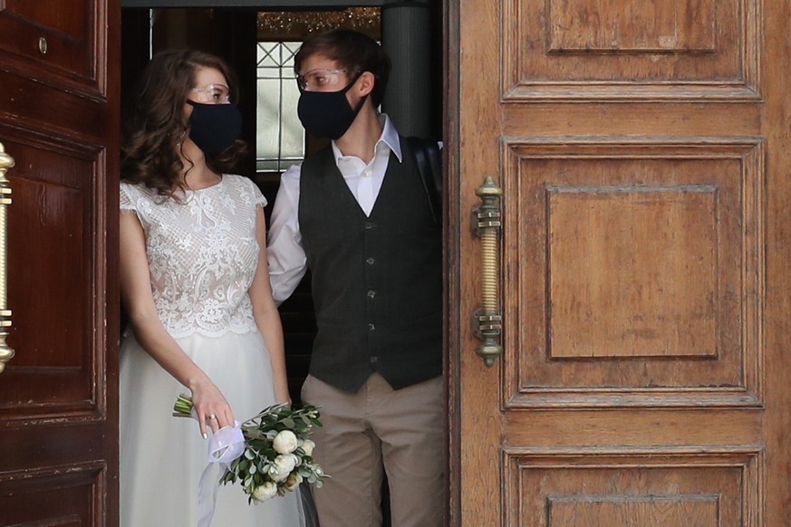 26.04.2020, Russland, Moskau: MOSCOW, RUSSIA - APRIL 26, 2020: A newlywedded couple in face masks are seen after their wedding ceremony at Moscow&#039;s No1 Civil Registry Office (Griboyedovsky) on th ...