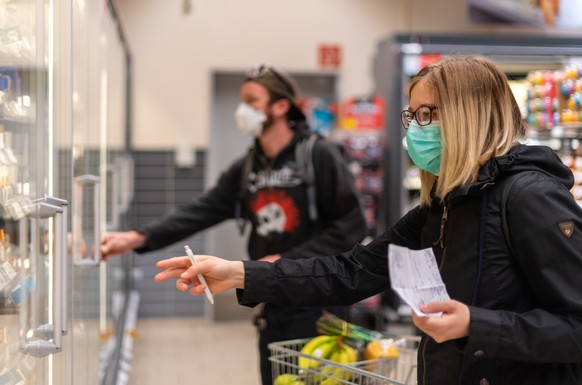 20.04.2020, Sachsen, Dresden: Kunden gehen in einem Supermarkt einkaufen und tragen dabei Mundschutz. Am heutigen Montag werden die ersten Corona-Auflagen schrittweise gelockert, in Sachsen gilt im Ei ...