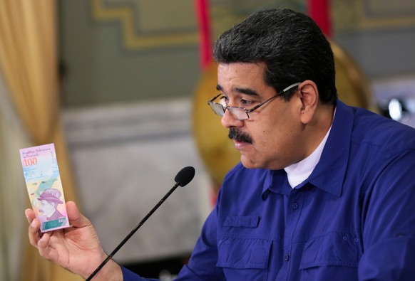 Venezuela&#039;s President Nicolas Maduro holds a bank note of the new Venezuela&#039;s currency Bolivar Soberano (Sovereign Bolivar) as he speaks during a meeting with ministers at Miraflores Palace  ...