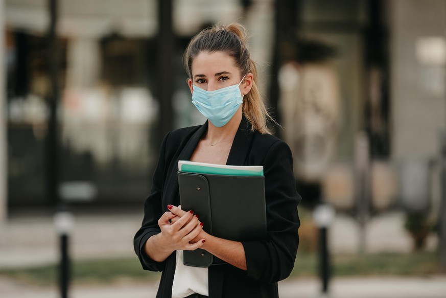 young business woman going to work down the street wearing medical mask
