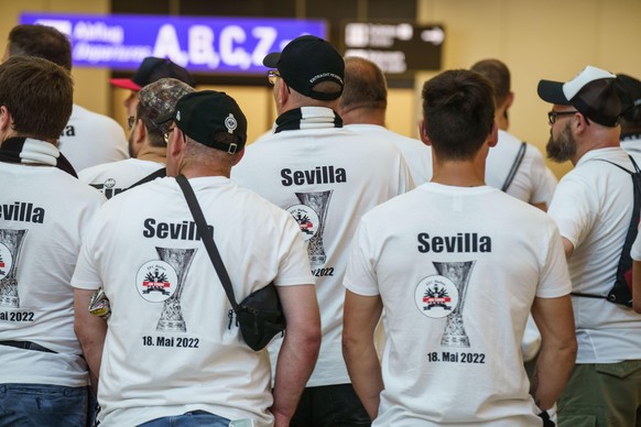 Fans des Fußball-Bundesligisten Eintracht Frankfurt in ihren weißen T-Shirts warten am Morgen auf dem Frankfurter Flughafen am Abflugschalter. Zum Finale der Europa League gegen die Glasgow Rangers in ...