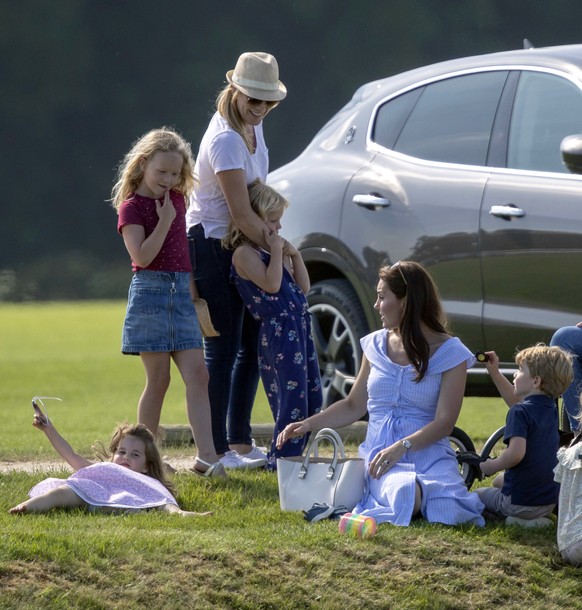 Britain&#039;s Kate, the Duchess of Cambridge, second right, sits with Prince George and Princess Charlotte as she talks to Autumn Phillips and her children, Savannah and Isla, as they watch Prince Wi ...