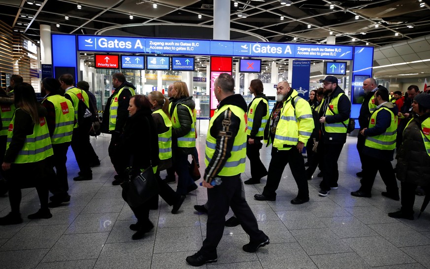 Members of Germany's union Verdi wear yellow vests as they march in front of Gate A of Duesseldorf Airport during a strike by Verdi, which called on security staff at Duesseldorf, Cologne and Stuttgar ...