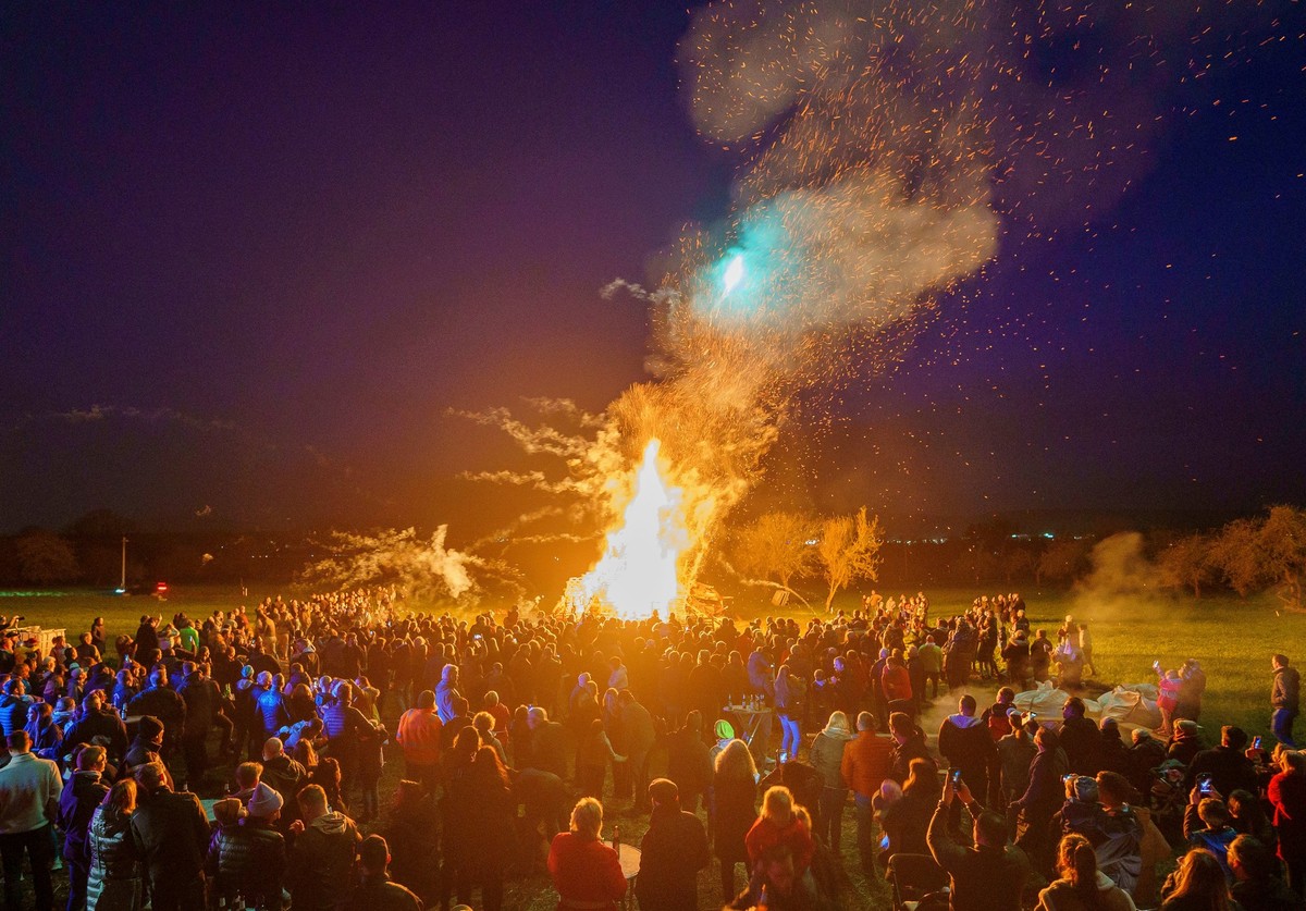 ARCHIV - 30.03.2024, Hessen, Friedrichsdorf: RECROP - Viele Menschen stehen um das Osterfeuer herum. Der Kerbeverein im Friedrichsdorfer Ortsteil Burgholzhausen veranstaltet sein traditionelles Osterf ...