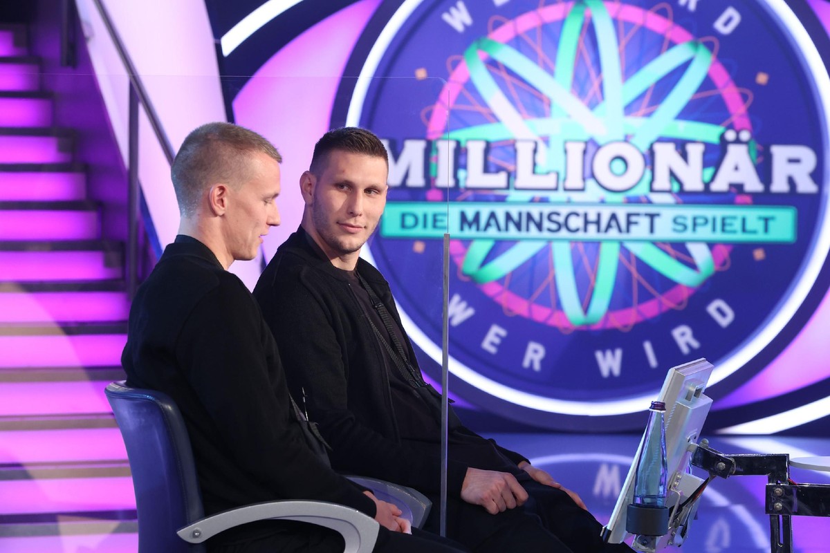Moderator Günther Jauch mit (hi., v.l.) Lukas Klostermann, Niklas Süle, Oliver Bierhoff, Kevin Trapp. (vo., v.l.) Leon Goretzka, Joshua Kimmich. Im Hintergrund steht das "Team hinter dem Team&quo ...
