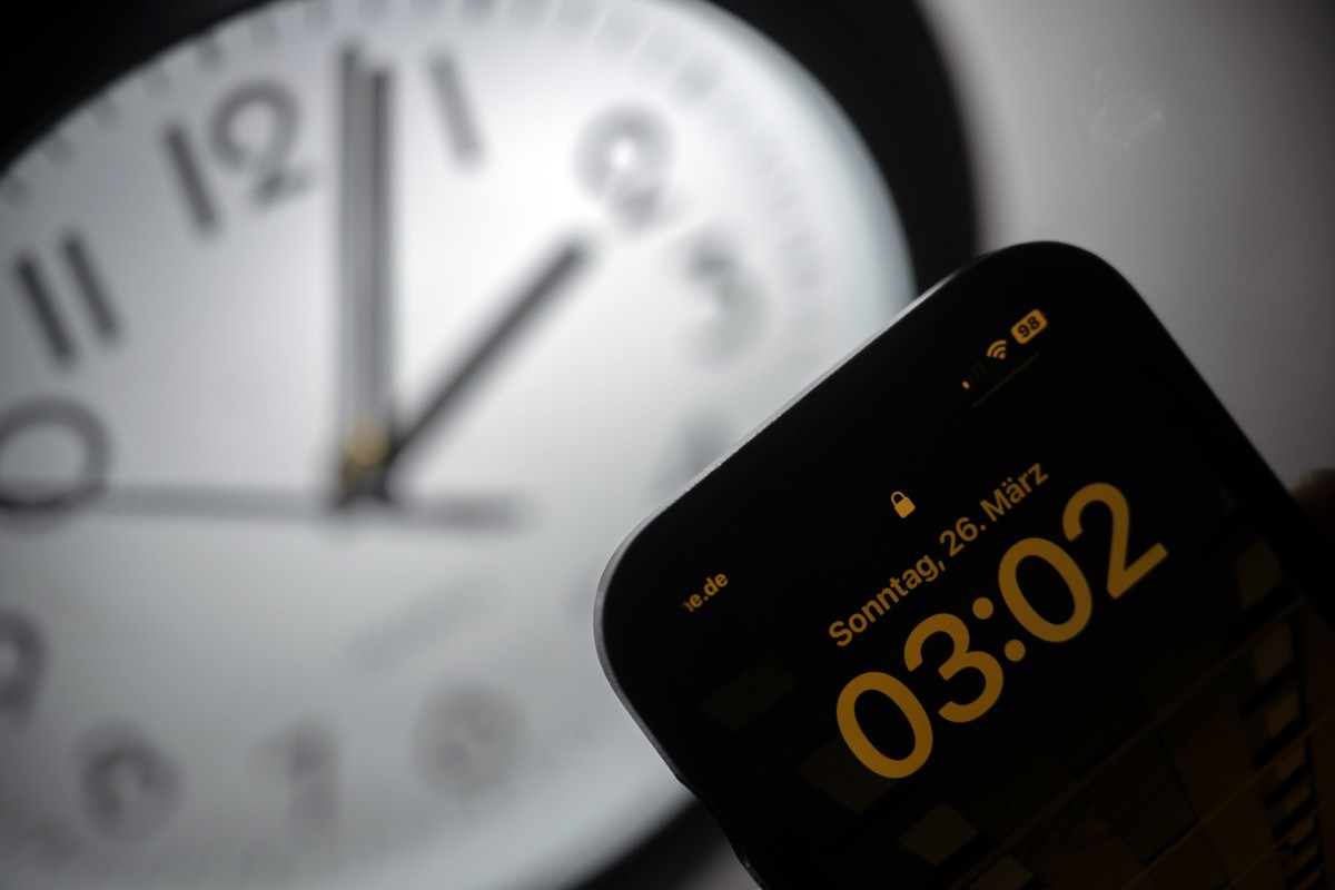 PRODUKTION - 21.03.2023, Hessen, Gießen: Ein Smartphone zeigt die Uhrzeit «03:03» an, während auf einer analogen Uhr noch 02:03 Uhr ist. Am 26. März werden die Uhren um 02:00 Uhr auf 03:00 Uhr vorgest ...