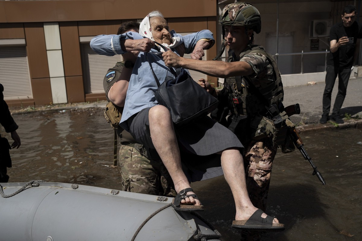 07.06.2023, Ukraine, Cherson: Eine Frau wird aus einem überschwemmten Viertel in evakuiert. Nach der Zerstörung des Kachowka-Staudamms in der Südukraine sind laut Angaben der russischen Besatzer im vo ...