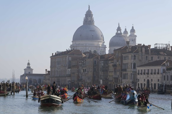 28.01.2024, Italien, Venedig: Boote fahren während der traditionellen Ruderparade, die Teil des Karnevals von Venedig ist. Mit einer großen Bootsparade durch die Kanäle der italienischen Lagunenstadt  ...