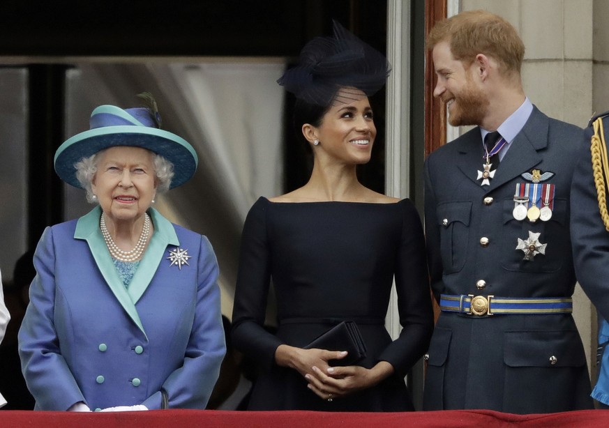 FILE - In this Tuesday, July 10, 2018 file photo Britain's Queen Elizabeth II, and Meghan the Duchess of Sussex and Prince Harry watch a flypast of Royal Air Force aircraft pass over Buckingham Palace ...