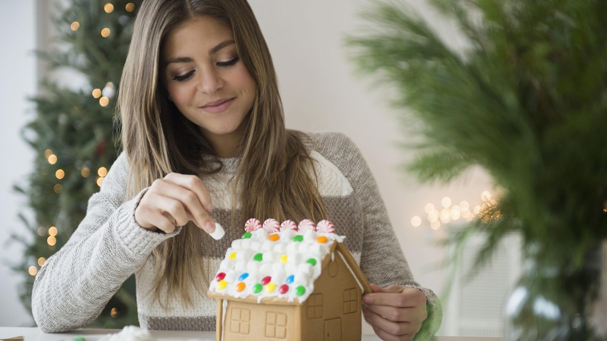 Young woman preparing gingerbread house || Modellfreigabe vorhanden