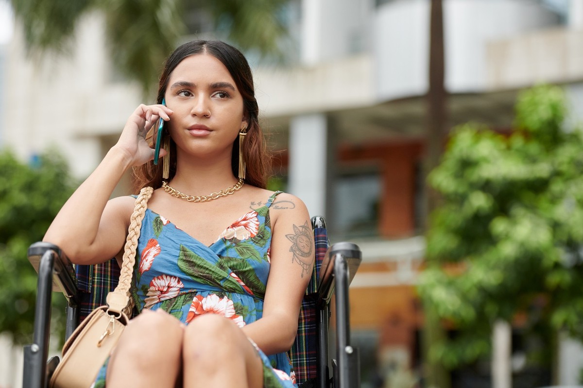 Portrait of pensive young woman in wheelchair talking on phone xkwx call talk communication wheelchair college technology smartphone online connection serious answer student woman portrait a11y wirele ...