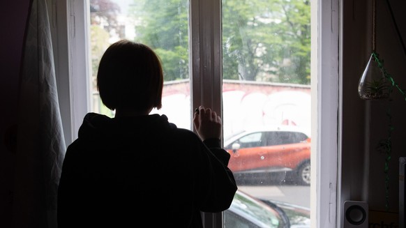 ARCHIV - 15.05.2021, Brandenburg, Potsdam: ILLUSTRATION - Eine Jugendliche blickt aus einem Fenster. Viele junge Menschen in Deutschland f