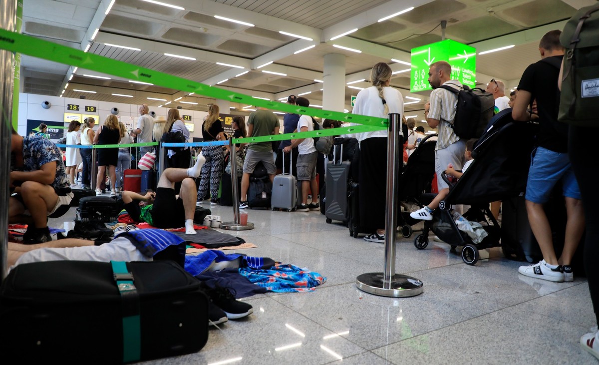 15.08.2024, Spanien, Palma: Reisende stehen im Flughafen von Palma de Mallorca Schlange. Ein heftiges Unwetter im spanischen Mittelmeerraum brachte den Flugverkehr auch auf Mallorca durcheinander. Ges ...