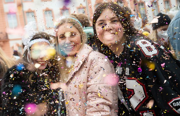 Frauen werfen zur Verlesung des närrischen Grundgesetzes auf dem Schillerplatz Glitzerkonfetti. Mitfeiern darf nur, wer vorab ein Ticket gekauft hat. Auf dem Schillerplatz gilt die 2G-Regel.