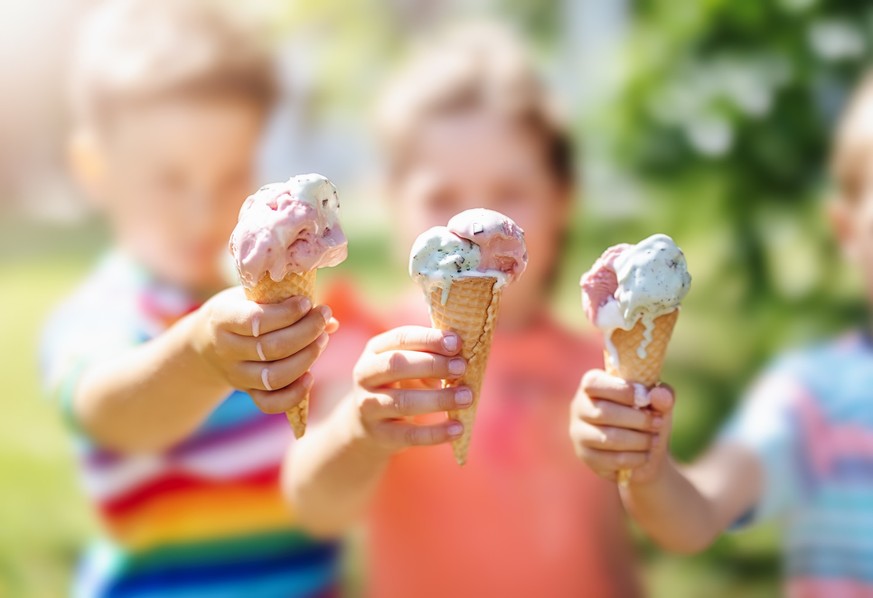 Group of children in the park eating cold ice cream. Concept of friendship and family relationship.