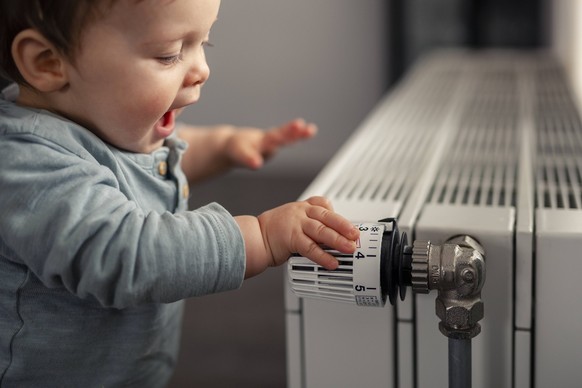 Excited baby boy playing with thermostat of heater model released Symbolfoto property released PUBLICATIONxINxGERxSUIxAUTxHUNxONLY SEBF00020