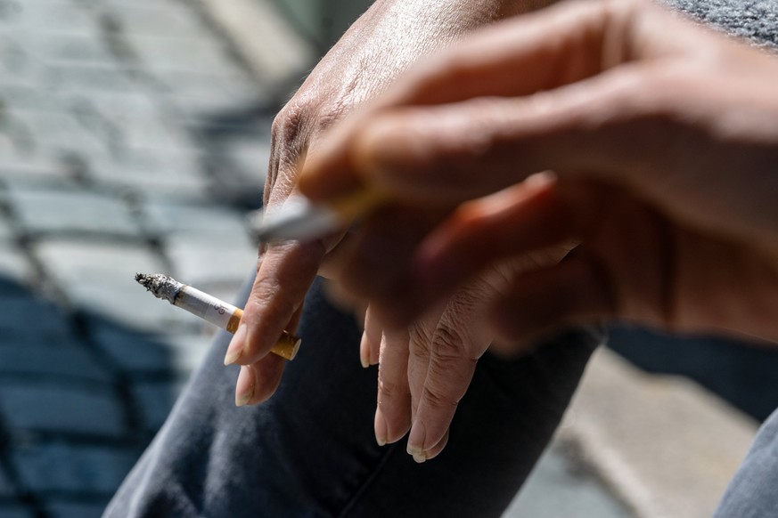 ARCHIV - 27.04.2021, Bayern, Amberg: Raucher halten eine brennende Zigarette in der Hand. Inzwischen rauchen weniger Menschen als noch vor zehn Jahren - zugleich kommen nach oft vielen Jahren des Rauc ...