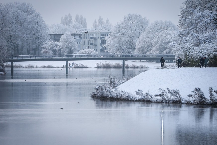 06.03.2023, Bremen: Radfahrer und Fußgänger sind auf dem verschneiten Deich des Werdersees unterwegs. Bei Temperaturen um den Gefrierpunkt zeigt sich die Hansestadt noch einmal winterlich. Foto: Focke ...