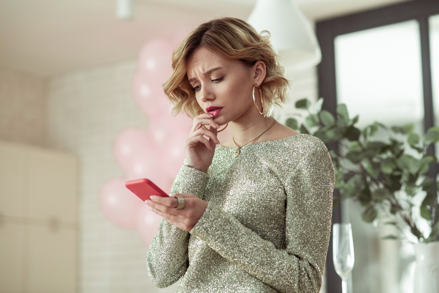 Reading message. Beautiful fashionable woman feeling stressed reading message from her man