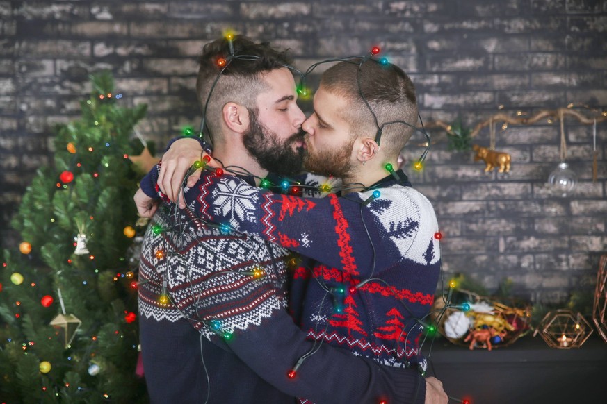 Kissing gay couple with chain of lights at Christmas time at home model released Symbolfoto property released PUBLICATIONxINxGERxSUIxAUTxHUNxONLY RTBF01049